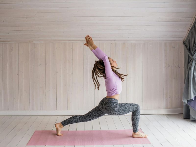 Person practicing yoga in a dark room with purple light.