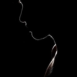 Silhouette of person stretching against a dark background.